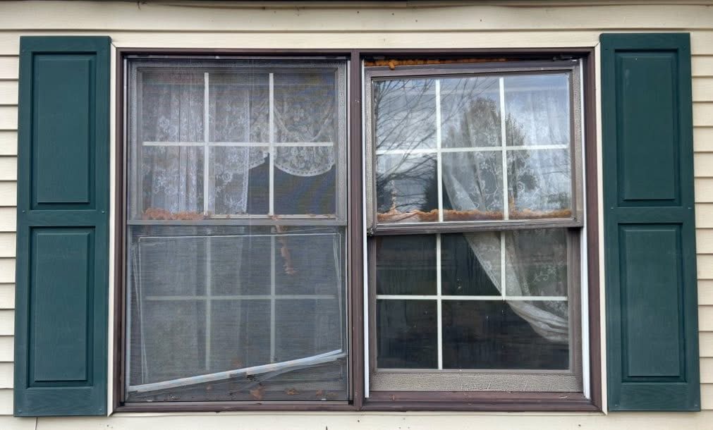 Medway home before replacement, with a failing double-hung and torn storm window